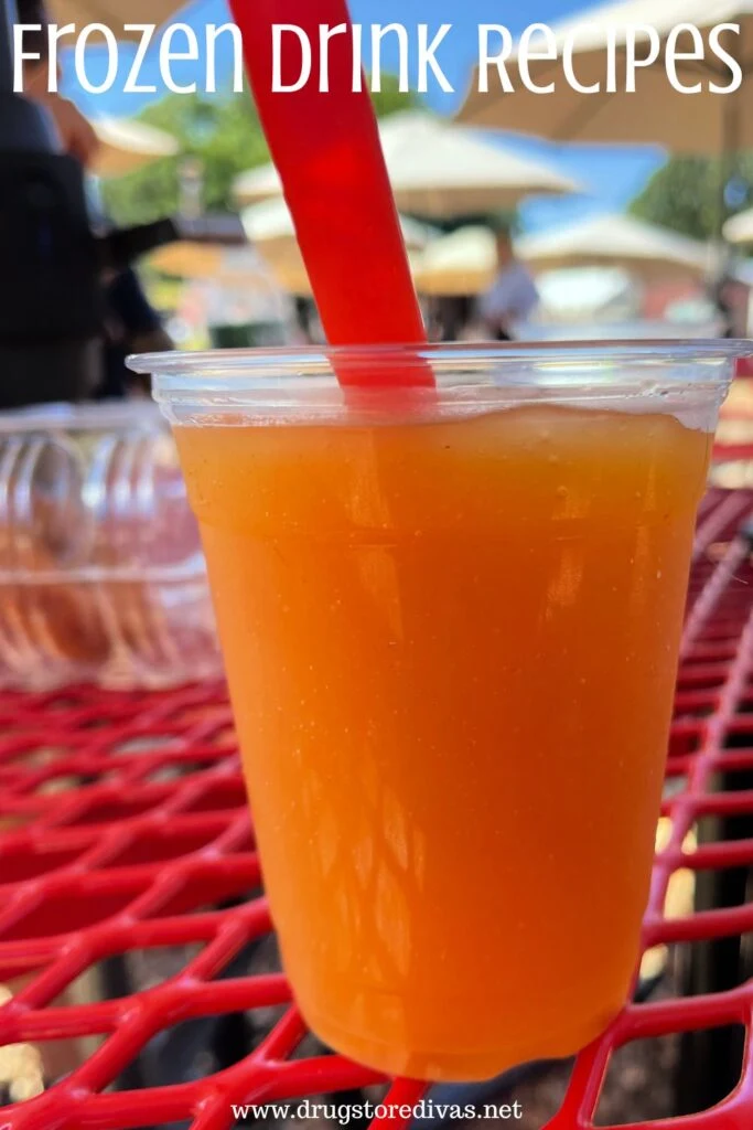 A frozen apple cider in a plastic cup with a straw on a red table with the words "Frozen Drink Recipes" digitally written on top.