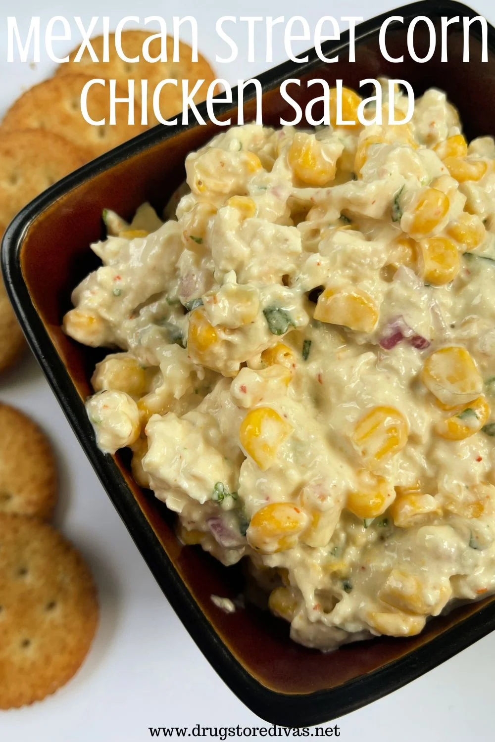 Chicken salad with corn in a bowl with crackers next to it and the words 