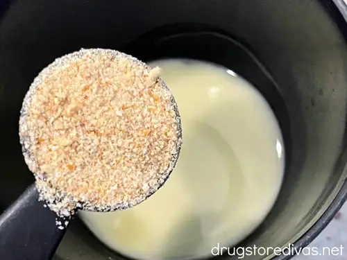 Bread crumbs in a measuring spoon above melted butter in a bowl.