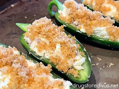 Unbaked stuffed jalapeno peppers on a baking sheet.