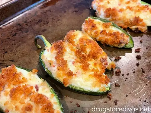 Baked stuffed jalapeno peppers on a baking sheet.