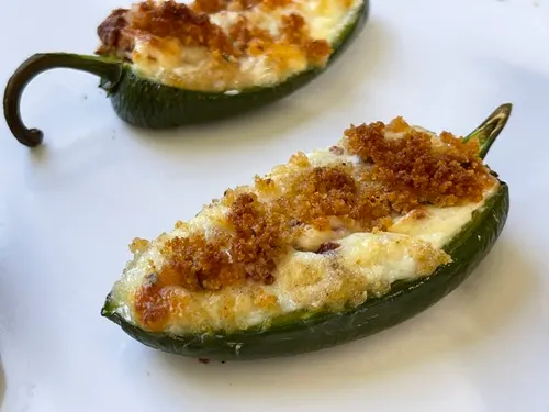 Baked stuffed jalapeno peppers on a white tray.