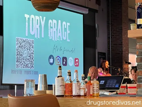 A woman on stage with a sign that says Tory Grace behind her at Assembly Food Hall in Nashville.