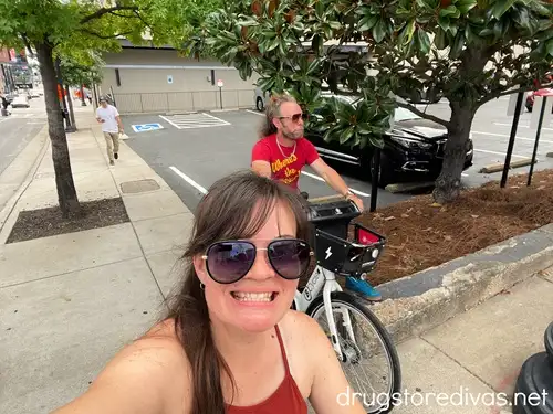 A woman in a maroon tank top and a man in a red t-shirt riding bikes in Nashville.