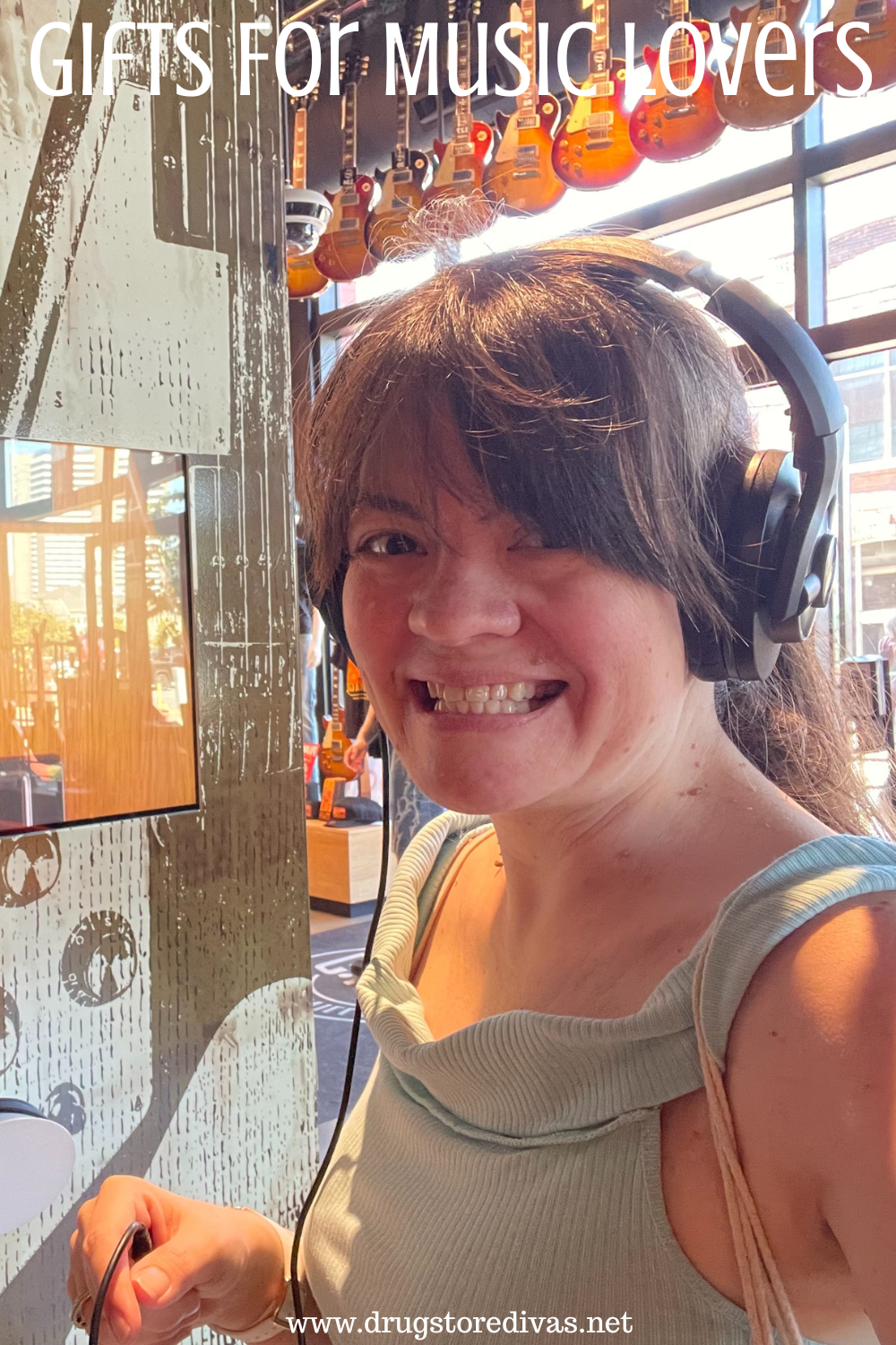 A woman in a blue sleeveless shirt with headphones on an a bunch of guitars behind her with the words 