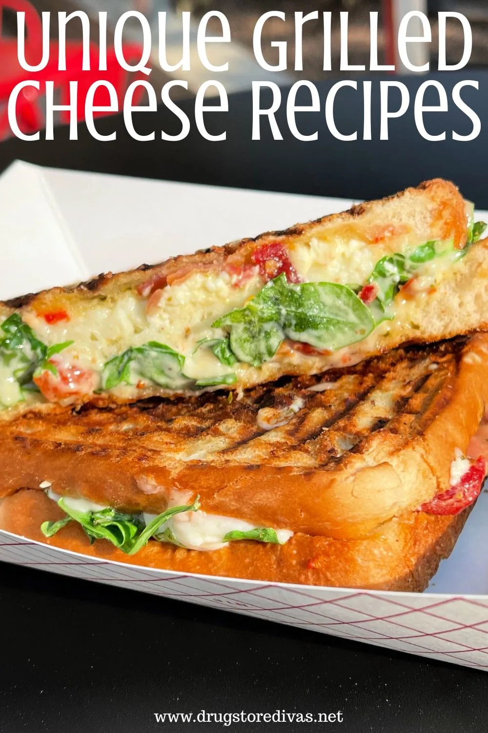 Two grilled cheese halves, one with basil and tomato, in a to go box with the words 