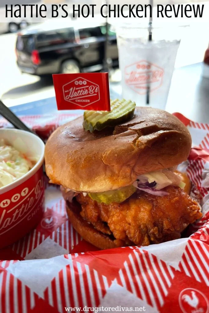 A chicken sandwich and coleslaw in a red bowl in a basket with red and white paper below it with a cup of water behind it and the words "Hattie B's Hot Chicken Review" digitally written on top.