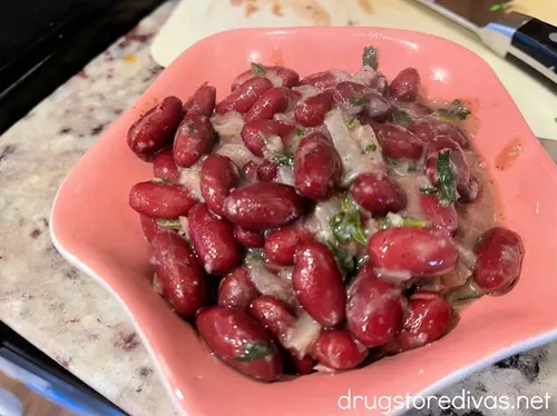 Dark red kidney beans and onions in a pink bowl.