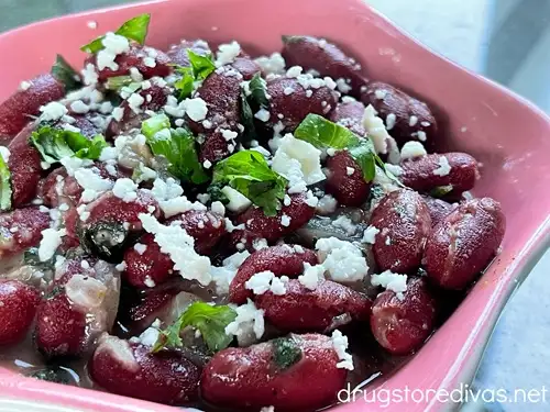 Dark red kidney beans, topped with cotija cheese and cilantro, in a pink bowl.