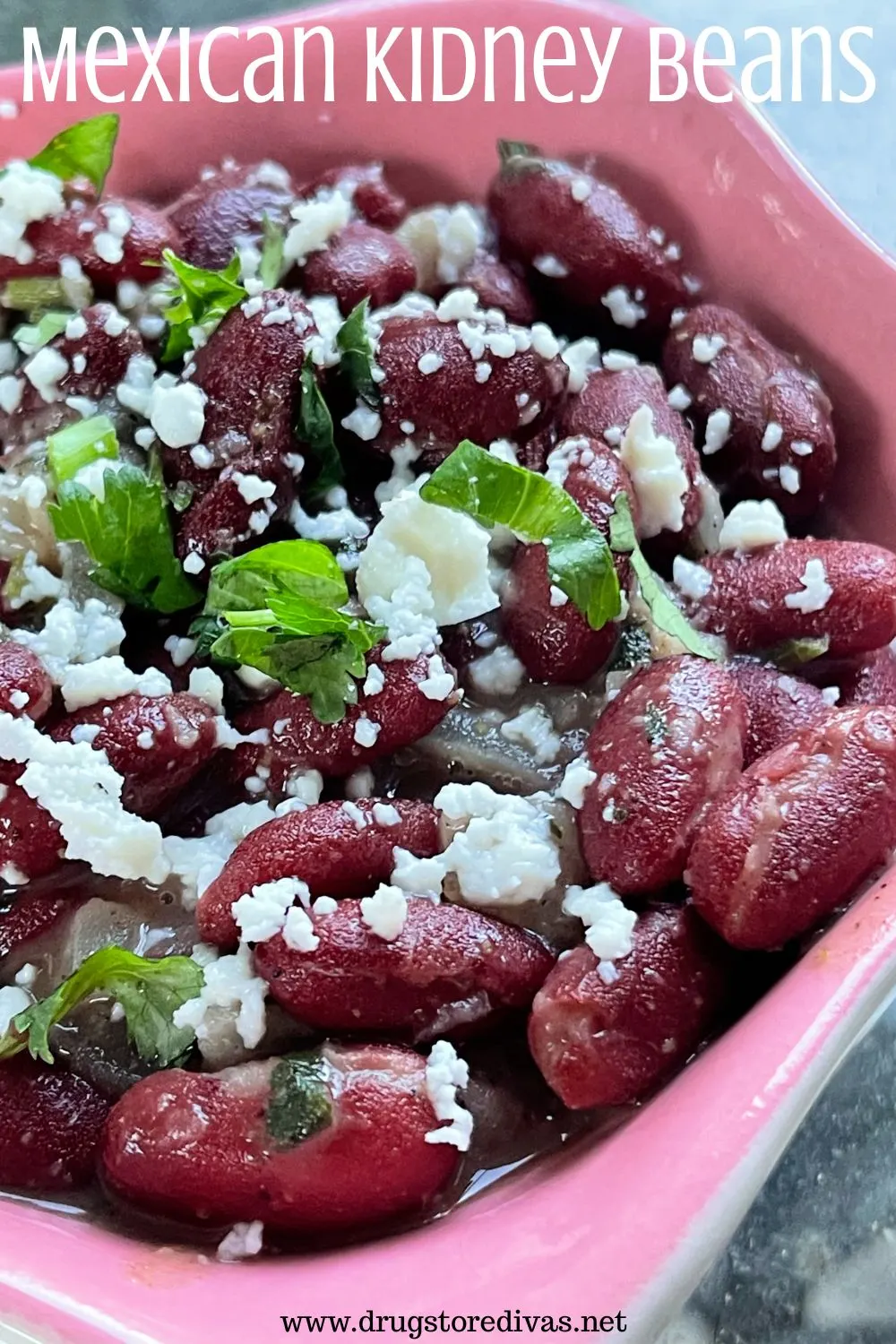 Dark red kidney beans topped with cilantro and cotija cheese in a pink bowl with the words 