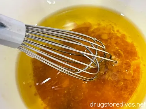 Olive oil in a white bowl being whisked.