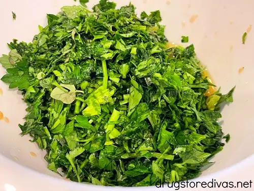 Chopped oregano and parsley in a white bowl.