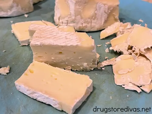 Slices of brie cheese on a blue cutting board.