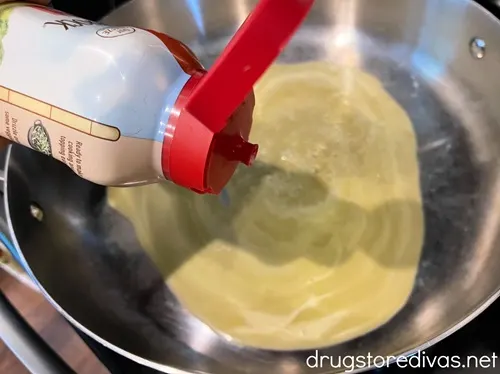 A container of butter above a skillet with melted butter in the bottom.