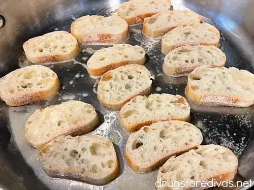 Pieces of French bread in a silver skillet.