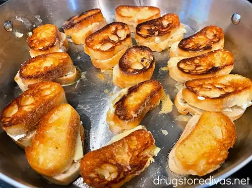 Pieces of toasted French bread in a silver skillet.