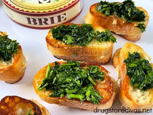 Mini grilled cheese sandwiches topped with chimichurri with a round container of brie cheese in the back.