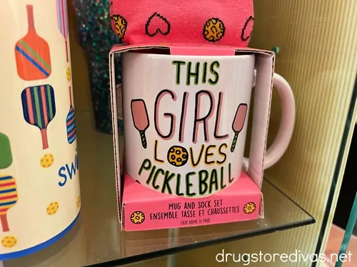 A mug in a box with a pair of socks that says "This Girl Loves Pickleball".