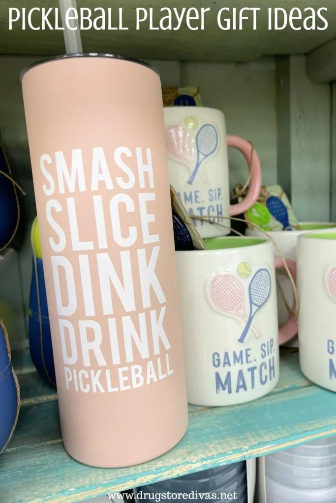A pink tumbler with a few mugs next to it on a shelf with the words "Pickleball Player Gift Ideas" digitally written on top.