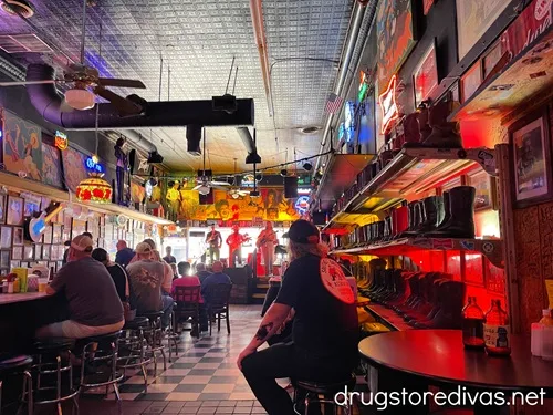 The inside of Robert's Western World in Nashville, with a band playing on a stage in the back, a bar to the left, rows of boots on the wall to the right, and patrons between.