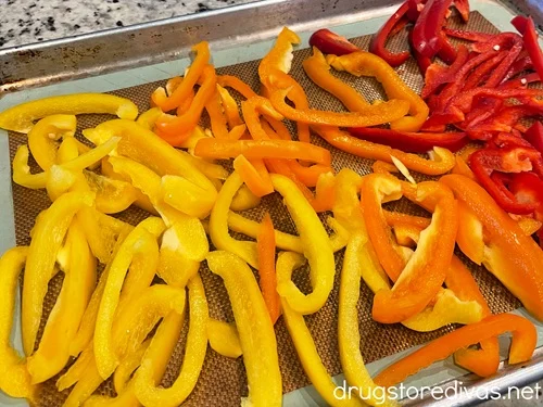 Yellow, orange, and red pepper slices on a sheet pan.