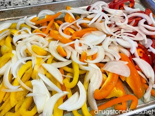 Sliced onion on top of slices of yellow, orange, and red peppers.