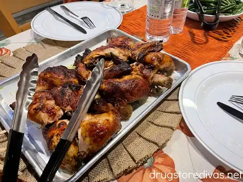 A tray of chicken on a table that's dressed for Thanksgiving.