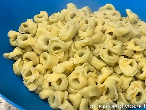 Cooked tortellini in a blue bowl.