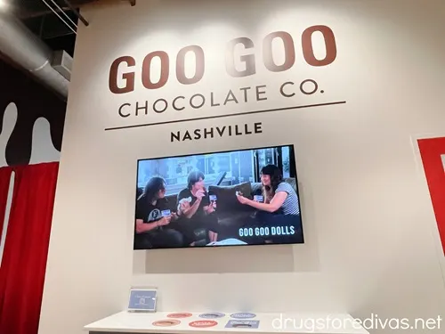 A wall that says Goo Goo Chocolate Co Nashville above a TV Screen, which has the Goo Goo Dolls band on the scfeen.