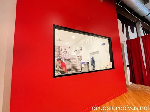 A red wall with a window where you can see chocolate makers working in Goo Goo Chocolate in Nashville.