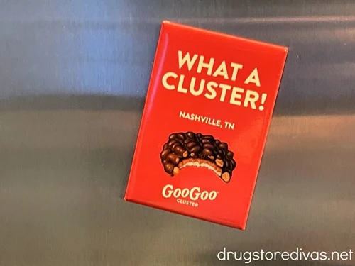 A red fridge magnet that says What A Cluster Nashville, TN on it with a picture of a Goo Goo Cluster.
