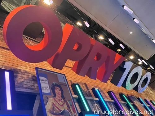 A large sign that says OPRY 100 with a painting underneath it.