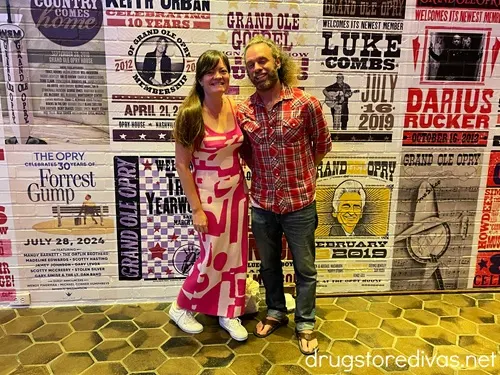 A woman and man standing in front of Grand Ole Opry posters.