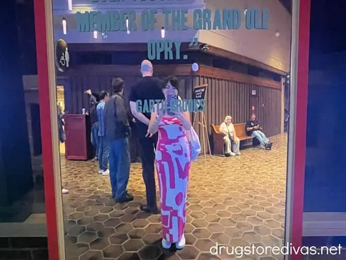 A woman in a dress in front of a mirror with a quote on it at the Grand Ole Opry.