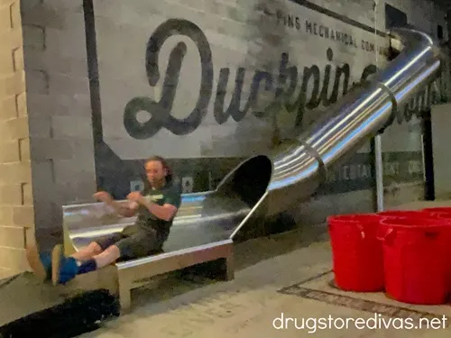 A man coming down a large slide at Pins Mechanical Co in Nashville.