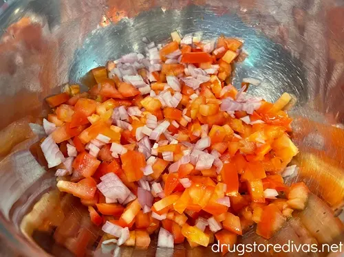 Diced tomatoes and shallots in a silver bowl.