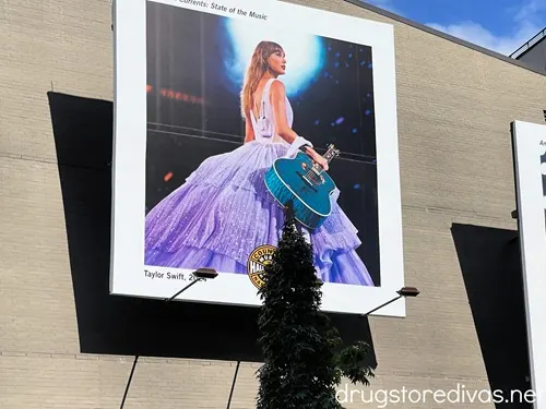 A poster of Taylor Swift in a purple dress from The Eras Tour hanging outside the Country Music Hall of Fame.