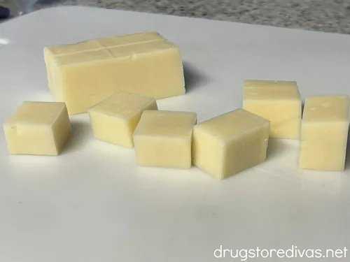 White cheese cut into cubes on a white cutting board.