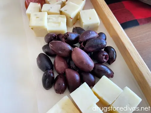 Kalamata olives on a tray between two piles of white cheese cubes.