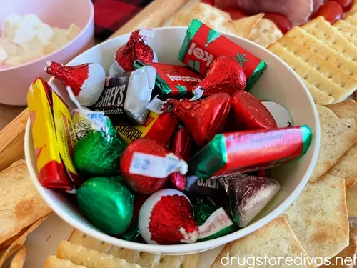 Christmas chocolates in a white bowl that's in the middle of two types of crackers on a tray.