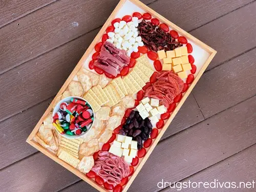 A charcuterie board, made of meats, cheese, olives, and tomatoes, that's shaped to look like a candy cane.