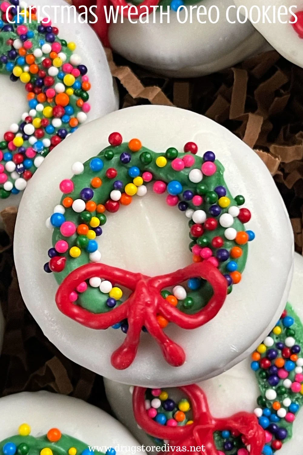 A white chocolate-dipped Oreo cookie with a candy wreath and bow on it with the words 