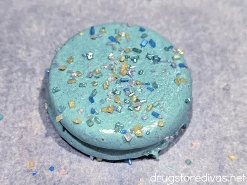 A blue chocolate dipped Oreo cookie with sugar sprinkles on it.