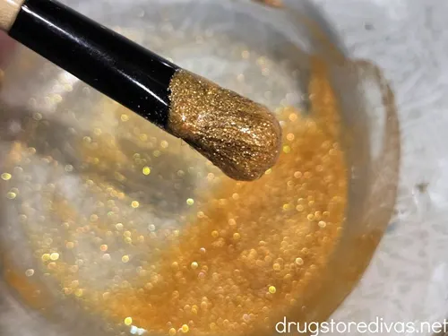 A bowl with gold edible glitter with a paint brush with the glitter.