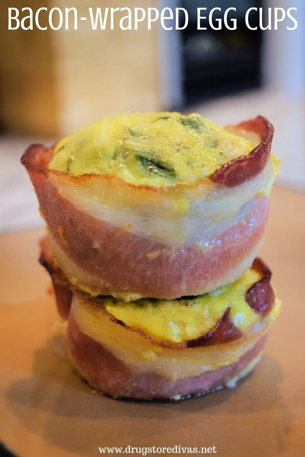 Two bacon-wrapped egg cups stacked on top of each other on a brown plate with the words "Bacon-Wrapped Egg Cups" digitally written on top.