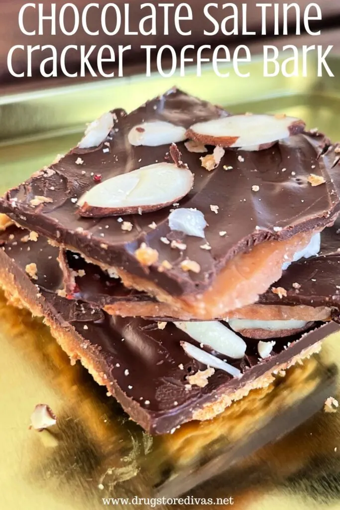 Pieces of toffee bark with almonds on top stacked on a gold tray with the words "Chocolate Saltine Cracker Toffee Bark" digitally written on top.