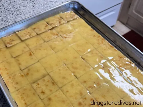 Saltine crackers on a tray with melted butter on top.