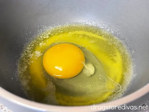 A raw egg cracked into a gray bowl.
