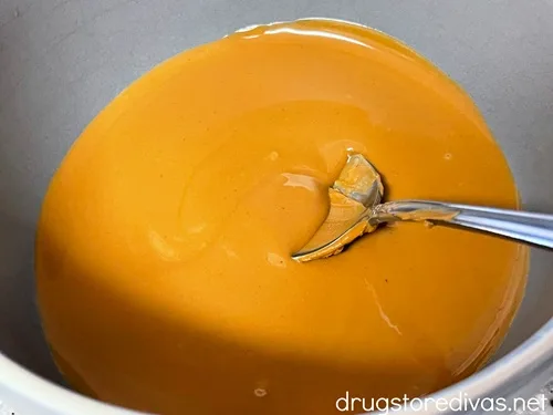 Melted cookie butter in a gray bowl with a spoon in it.