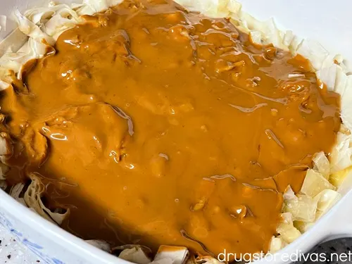 Melted cookie butter on top of phyllo dough strips that are in a white pan.